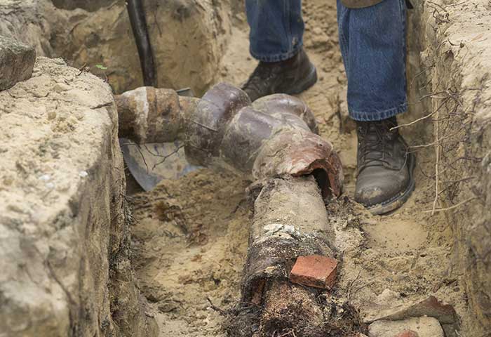 Person working on a pipe in an underground trench.