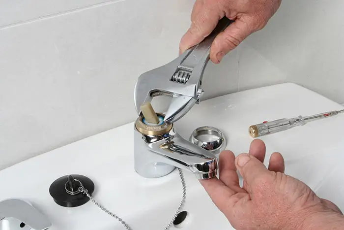 Plumber repairing a faucet with a wrench