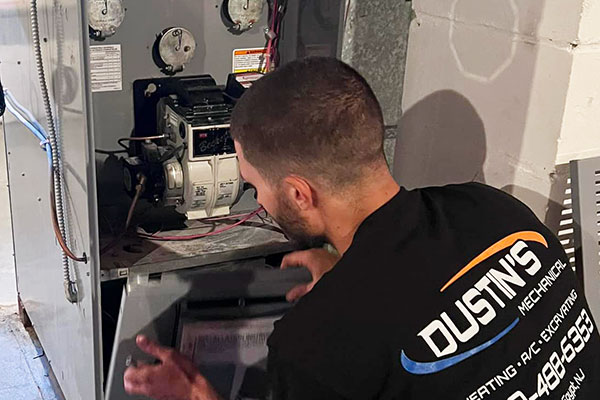 A technician from Dustin's Mechanical is inspecting an HVAC.